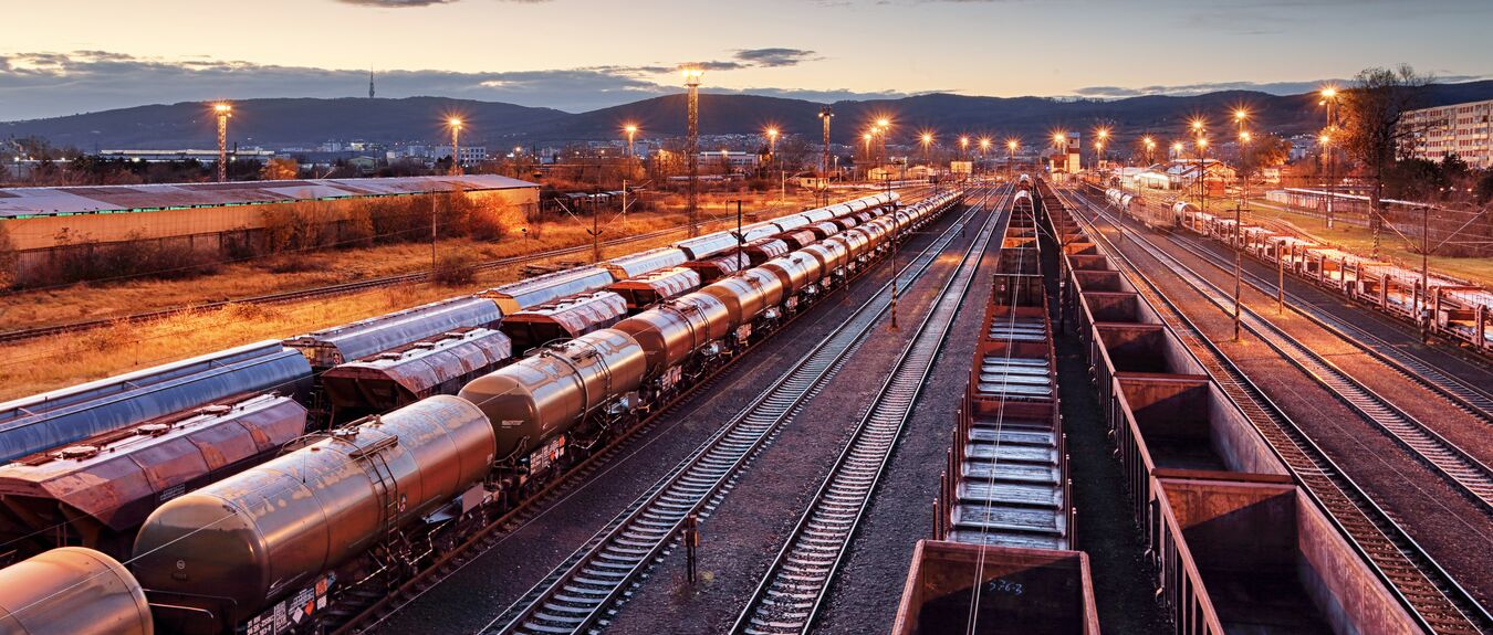Andén de tren de carga al atardecer con contenedores, trenes, ferrocarril